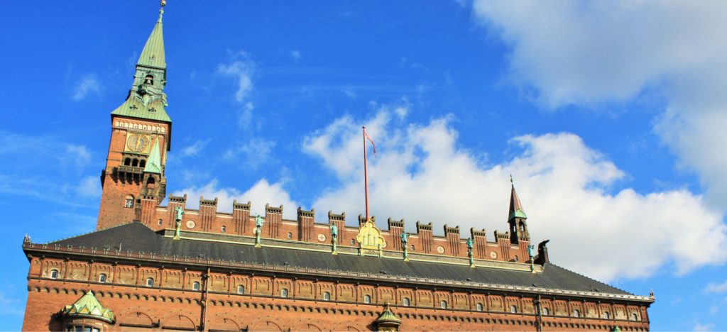 Københavns rådhus mod en blå sommerhimmel med hvide skyer.