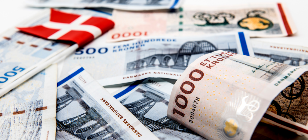 Montage med en række danske tusind og femhundrede kroners sedler og et lille bordflag som ligger ovenpå, med Dannebrog.