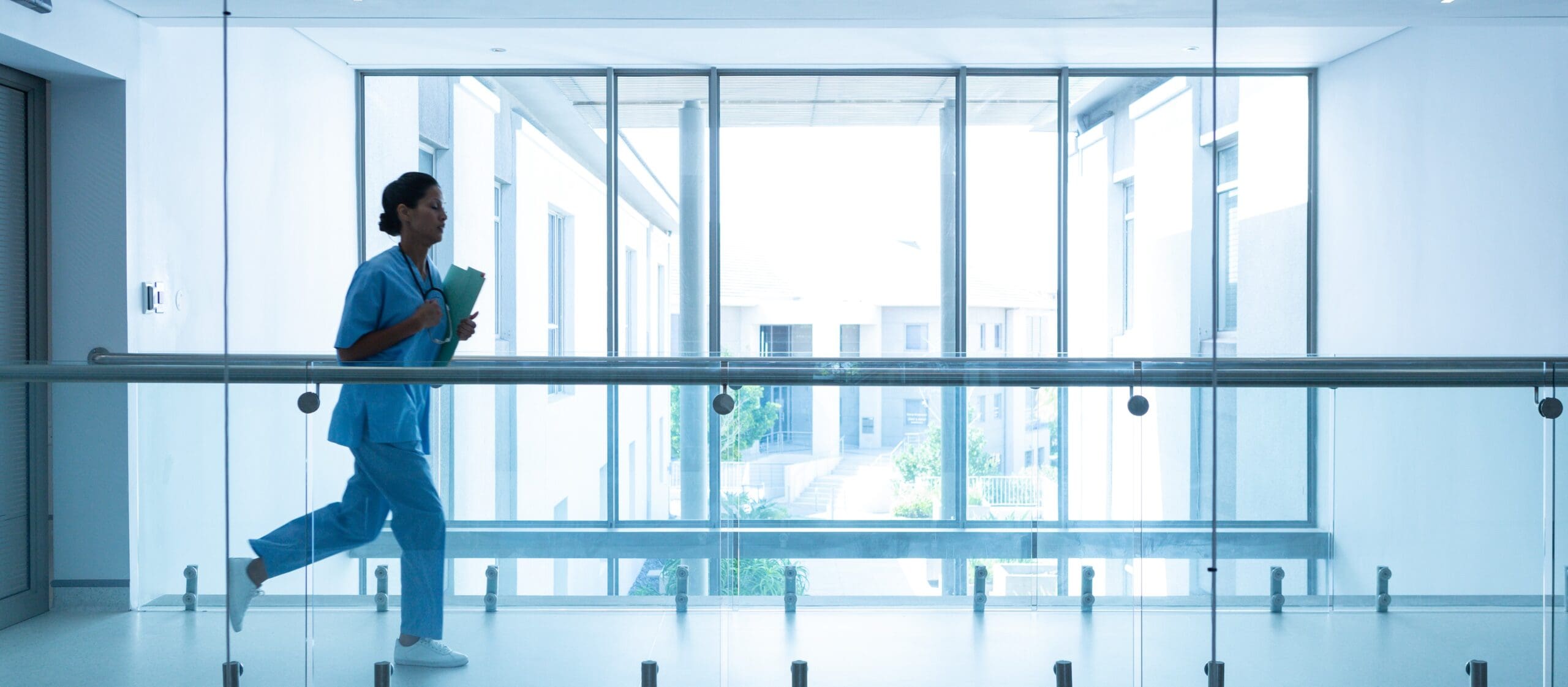 Female surgeon with medical reports running in corridor at hospital