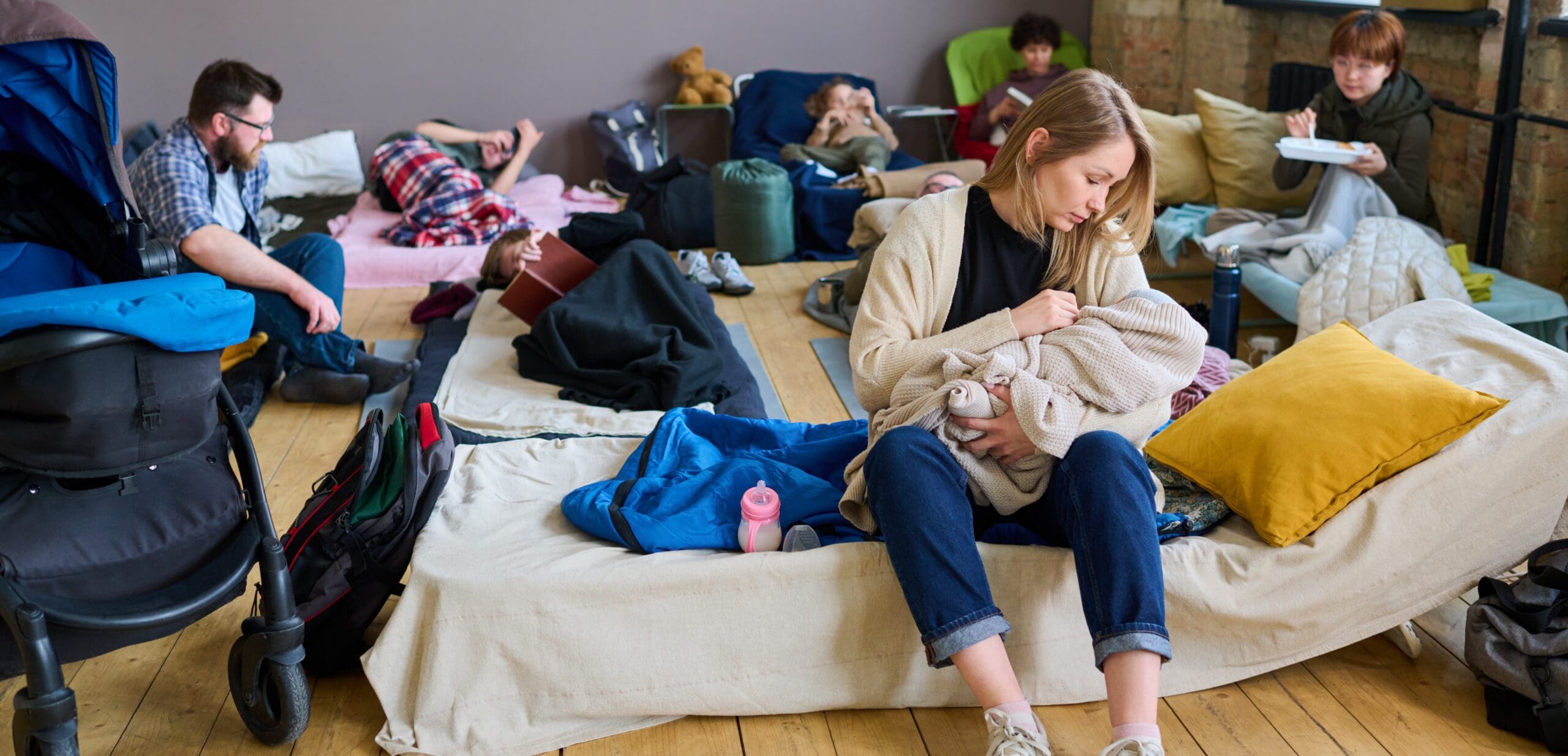 Young careful mother in casualwear lulling her baby wrapped into warm plaid